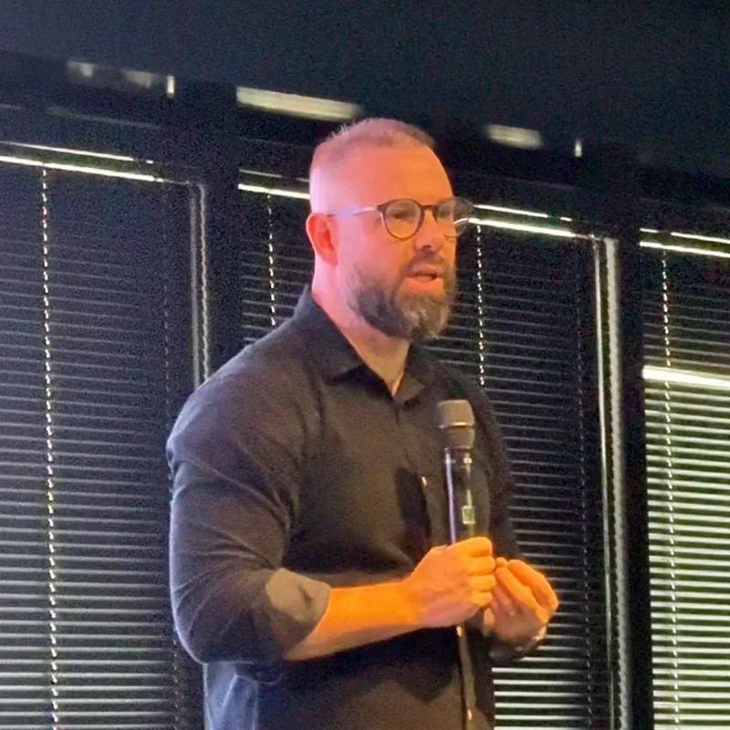 Alexandre Martins falando ao microfone no palco