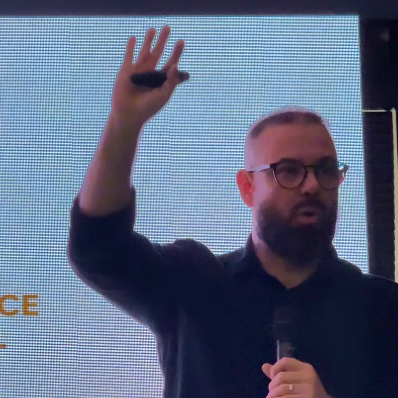 Alexandre Martins com a mão erguida, falando ao microfone